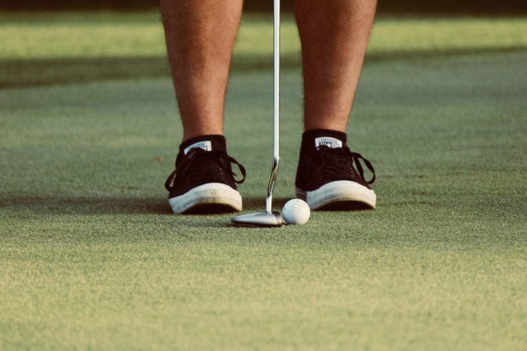 close up of feet with a putter and ball